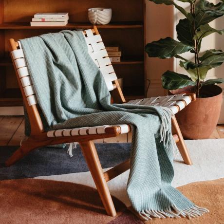Вафельное одеяло из переработанной шерсти цвета Sage накинуто на плетеный стул