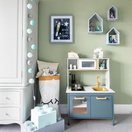 Szałwia zielony pokój dziecinny z niebieską kuchnią do zabawy, półkami na ścianie i białą szafą