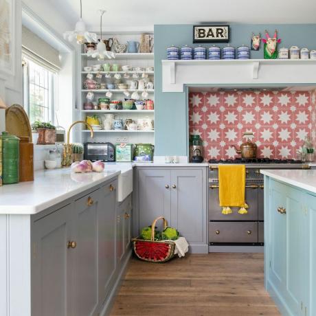 Cocina con gabinetes grises, isla azul y salpicadero de azulejos estampados