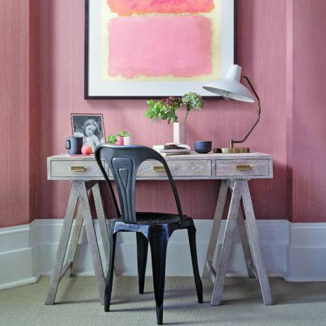 Domowe biuro z różowymi ścianami i pasującą grafiką na ścianie