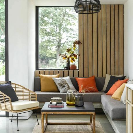 Obývací pokoj s dřevěným obložením stěn s pohovkami, polštářem a konferenčním stolkem
