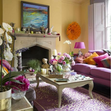 Gult rom, rosa sofa, veggmontert hodeplagg med oransje fjær