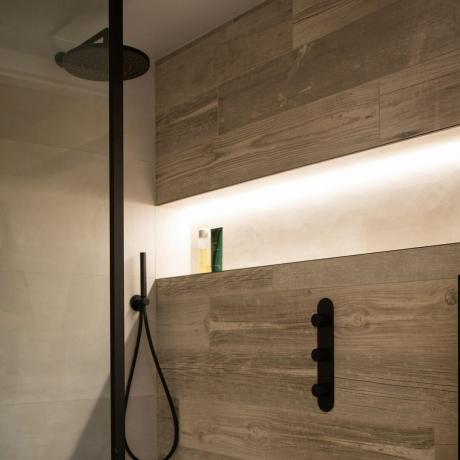 drewniana ściana prysznicowa z czarną głowicą prysznicową