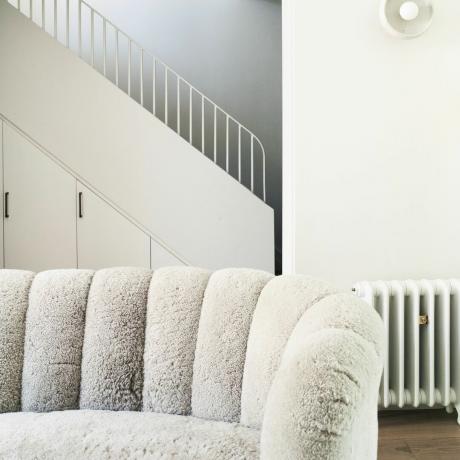 Un canapé bouclé blanc matelassé avec un escalier en arrière-plan