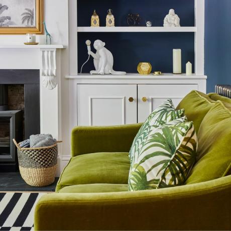 Zelená sametová pohovka v obývacím pokoji s vestavěnými policemi a modrými stěnami