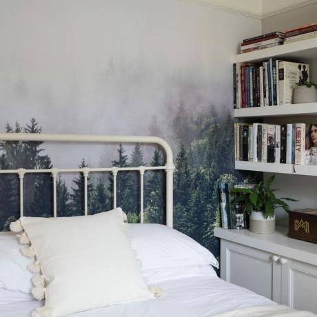 Spalnica z gozdno stensko poslikavo, belo bolniško posteljo, knjižno polico in belo posteljnino