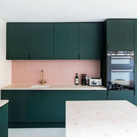 mörkgrönt kök med rosa stänk och matbord