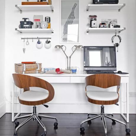 biela domáca kancelária s dvoma drevenými otočnými stoličkami a nástennými policami