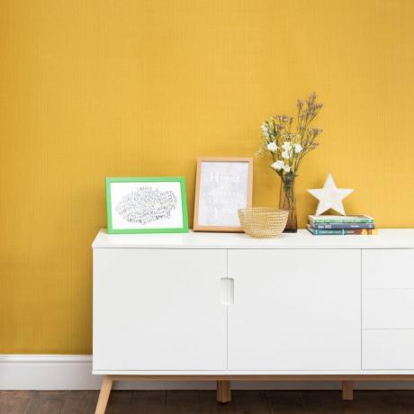 En hall med en vit skänk mot en gul vägg