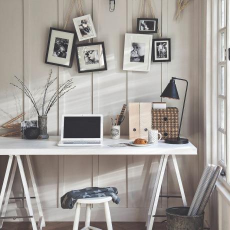 Otthoni iroda íróasztallal és bekeretezett fényképekkel a falon
