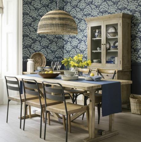 sala de jantar com papel de parede padrão azul e abajur pendente em vime