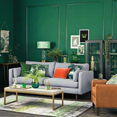 Ruang tamu hijau zamrud dengan sofa abu-abu pintar dan aksen oranye