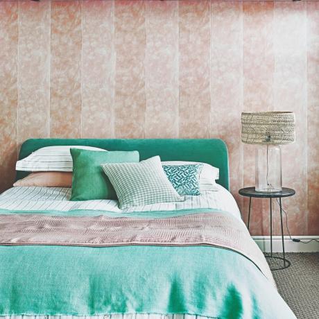 Et soveværelse med et lyserødt tapet og turkis sengetøj