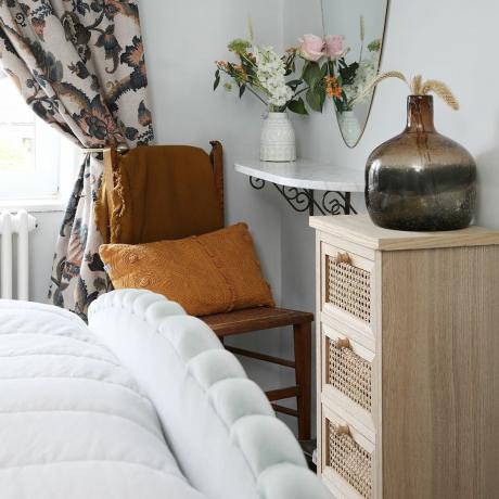 Camera da letto con cassettiera, vasi, poltrona, specchio decorativo a parete