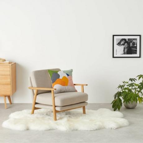 Helgar Large Quad Sheepskin Rug in Weiß auf Wohnzimmerboden unter einem grauen Sessel