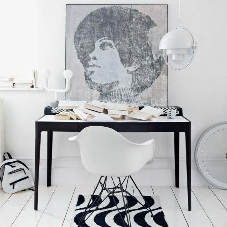 Mustavalkoinen kotitoimisto ikonikuvalla ja Eames -tuoli