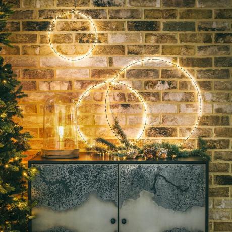 Anillos LED de Navidad iluminados en una pared de ladrillo encima de un aparador de metal