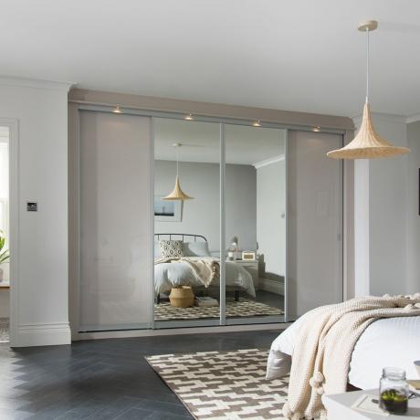 Nevtralno siva spalnica z omarami z drsnimi vrati in zrcalnimi paneli