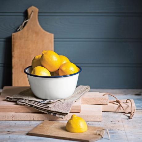 Zitrone in weißer Schüssel vor Holzbrett