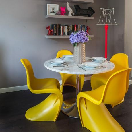 Salle à manger grise avec des chaises design de reproduction jaune vif