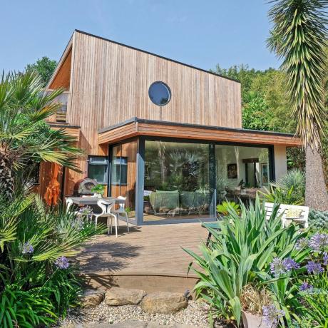 moderní dům s dřevěnou horní polovinou a skleněnou zahradní místností