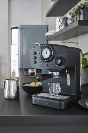 uma máquina de café expresso preto em uma bancada em uma cozinha