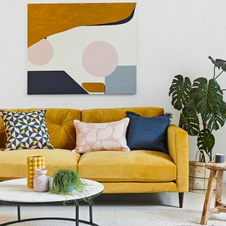 ספה חרדלית עם כריות צבעוניות לפי יצירות אמנות וצמח בית