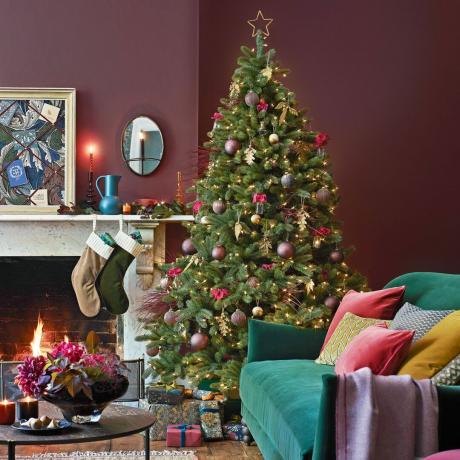 purpura viesistaba ar Ziemassvētku eglīti un kamīnu