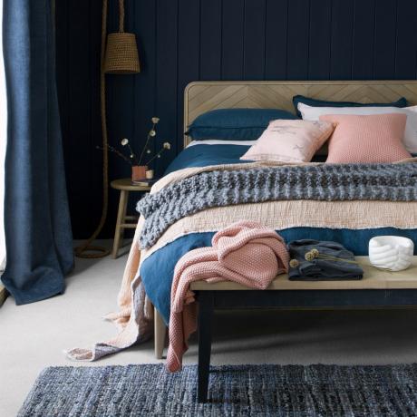 Polnočná modrá spálňa s drevenou posteľou a vlneným kobercom