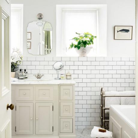Baltas vonios kambarys su metro sienų plytelėmis ir kreminiu praustuvu unti