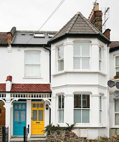 Vitt vickfront hus med gul ytterdörr