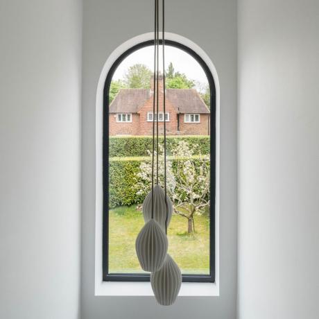 una finestra ad arco in un corridoio con una lampada a sospensione