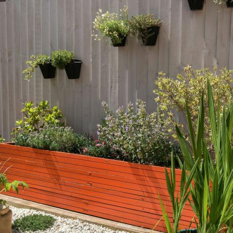 Rustfarget opphøyd plantekasse med vegghengte plantepotter