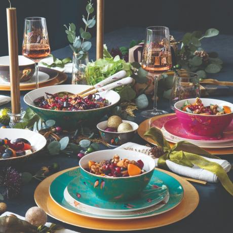 Пищна маса с цветни купи и чинии и салфетки със златни панделки