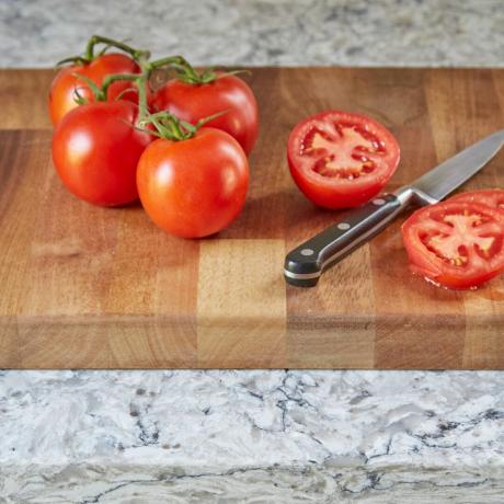 Pomidorai ant medinės pjaustymo lentos šalia virtuvinio peilio, marmurinis virtuvės stalviršis