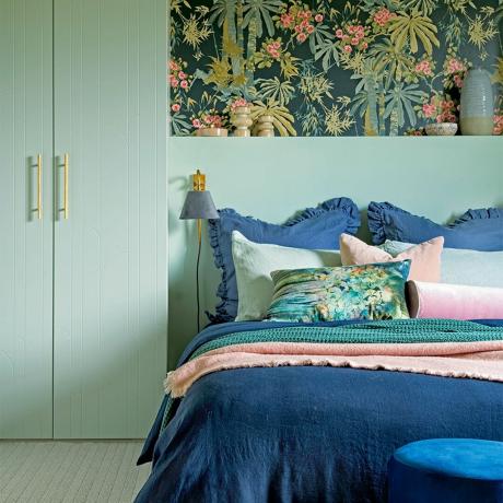 spavaća soba sa zelenim ormarima i tamnim tapetama s cvjetnim motivima