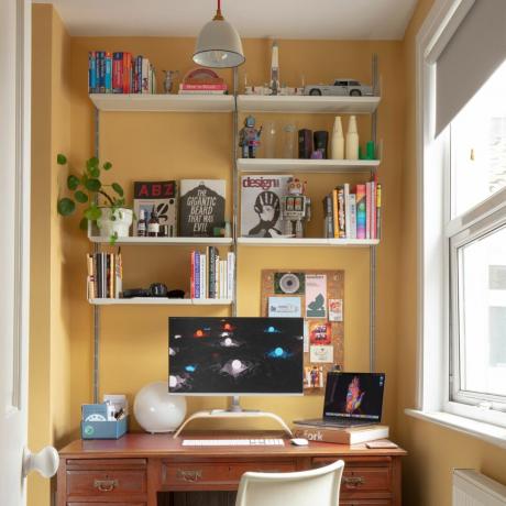 Namų biuro lentyna su įvairiais eksponuojamais daiktais, kompiuteris ir stalas