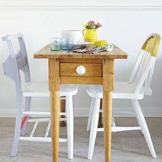Ruang makan putih dengan meja kayu ramping dan kursi pastel