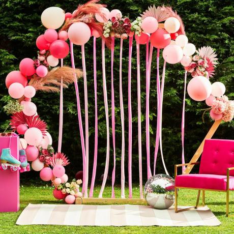 фотобудка в виде арки из воздушных шаров с розовым креслом для вечеринки в саду и барбикора