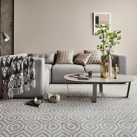 karpet geometris bermotif beige dengan sofa dan meja kopi