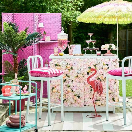 kültéri bár művirágos panelekkel, bárszékekkel és napernyővel a Barbiecore trendhez