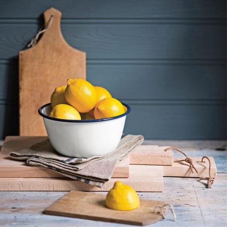 Skleda limon z enim rezom limone na leseni deski za rezanje