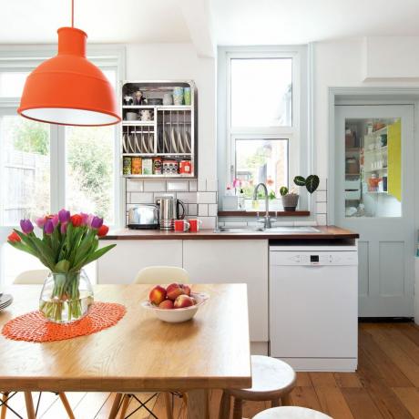 ahşap masa, turuncu tavan lambası ve bulaşık makinesi ile nötr mutfak