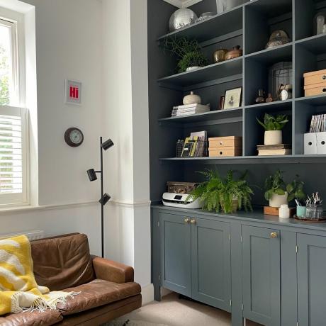 Thuiskantoor met grijs geschilderde boekenplanken ingericht met decoratieve items