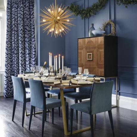 sala de jantar com paredes azuis escuras e luz dourada do sputnik