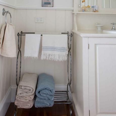 ванна кімната з рушниками, що висять на стелажі та стінових панелях