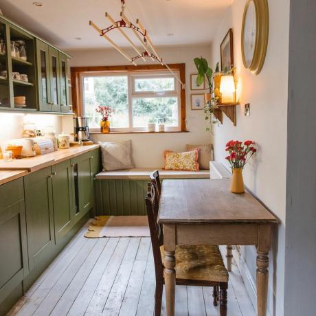 Çalkalayıcı dolaplar ve çiftlik evi masasıyla yeşil kır mutfağı makyajı.