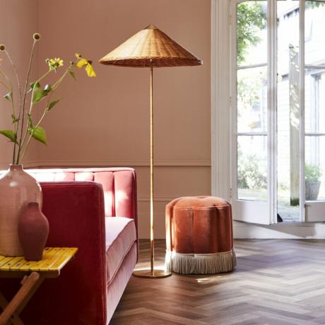 рожевий житловий простір з яскраво-рожевою будкою, рожевими стінами, рожевим пуфем, золотою лампою та дерев’яною підлогою