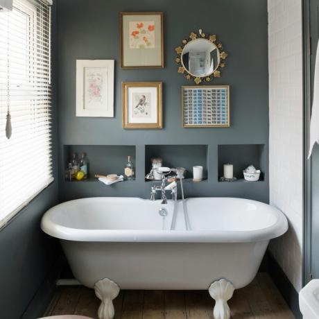 חדר אמבטיה אפור עם קיר גלריה של הדפסים ומראה מעל מדפי אחסון
