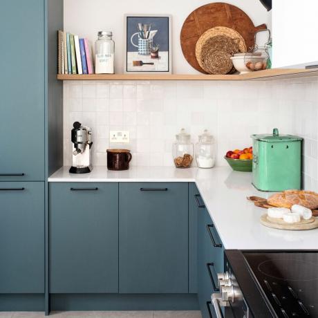 Blåmalede køkkenskabe og mørke greb, dekoreret køkkenbordplade